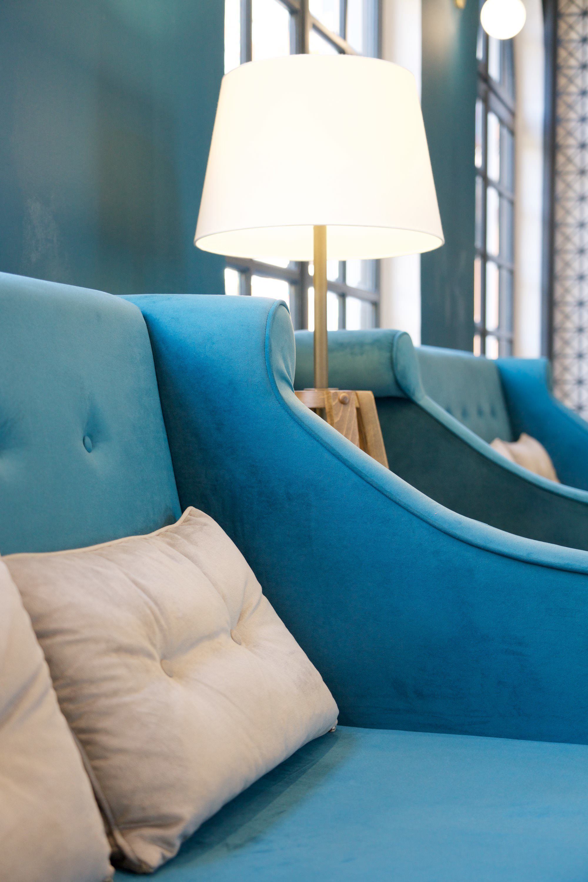 A blue sofa with a wooden frame and a white cushion.