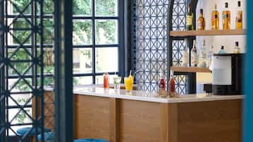 A bar area with wooden stools, a bar counter, and shelves with bottles.