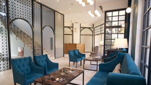 Un vestíbulo espacioso con una imponente escalera, asientos tapizados en azul y una mesa de centro de mármol.