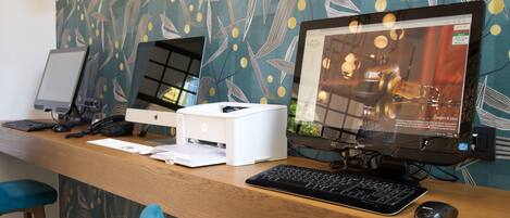 Un mostrador de recepción de hotel con una computadora de escritorio, una impresora y un teclado.