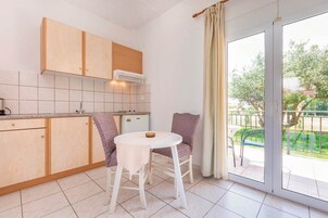 Una cocina compacta con armarios de madera, una encimera blanca y una mesa pequeña con sillas.