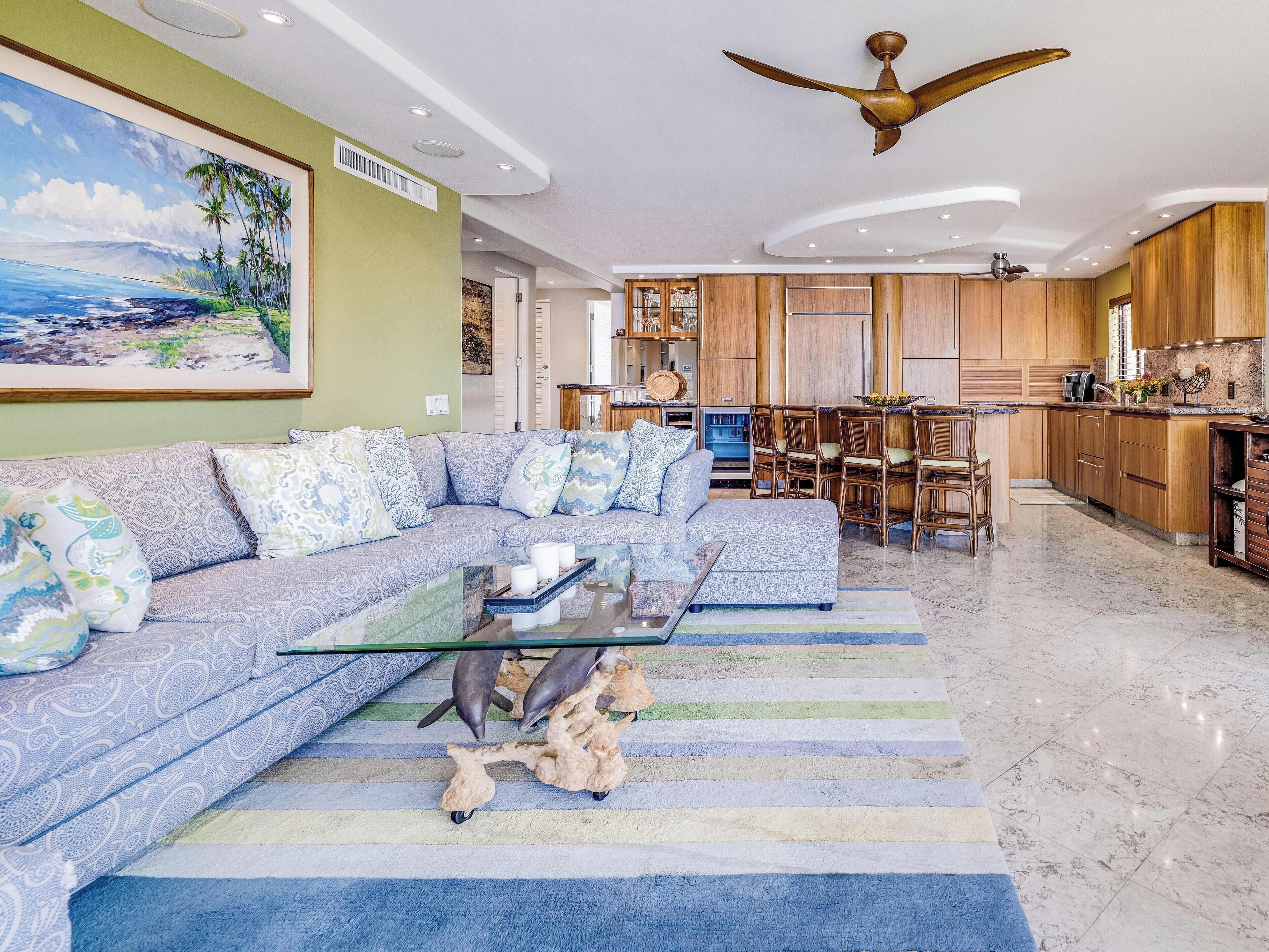 A modern living room with a sectional sofa, a glass coffee table, and a striped rug.