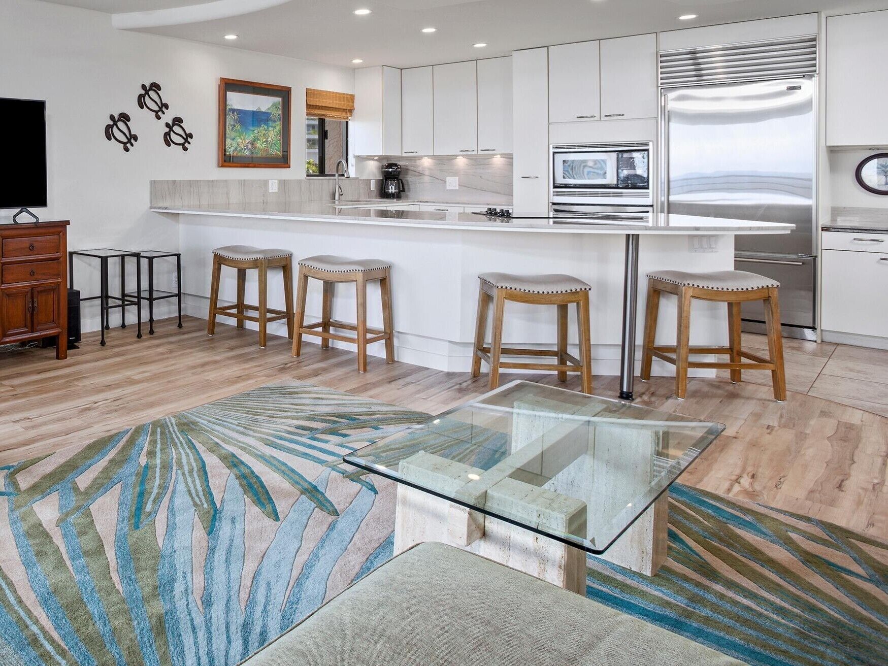 Una cocina moderna con armarios blancos, un refrigerador de acero inoxidable y una mesa de comedor con cubierta de vidrio.