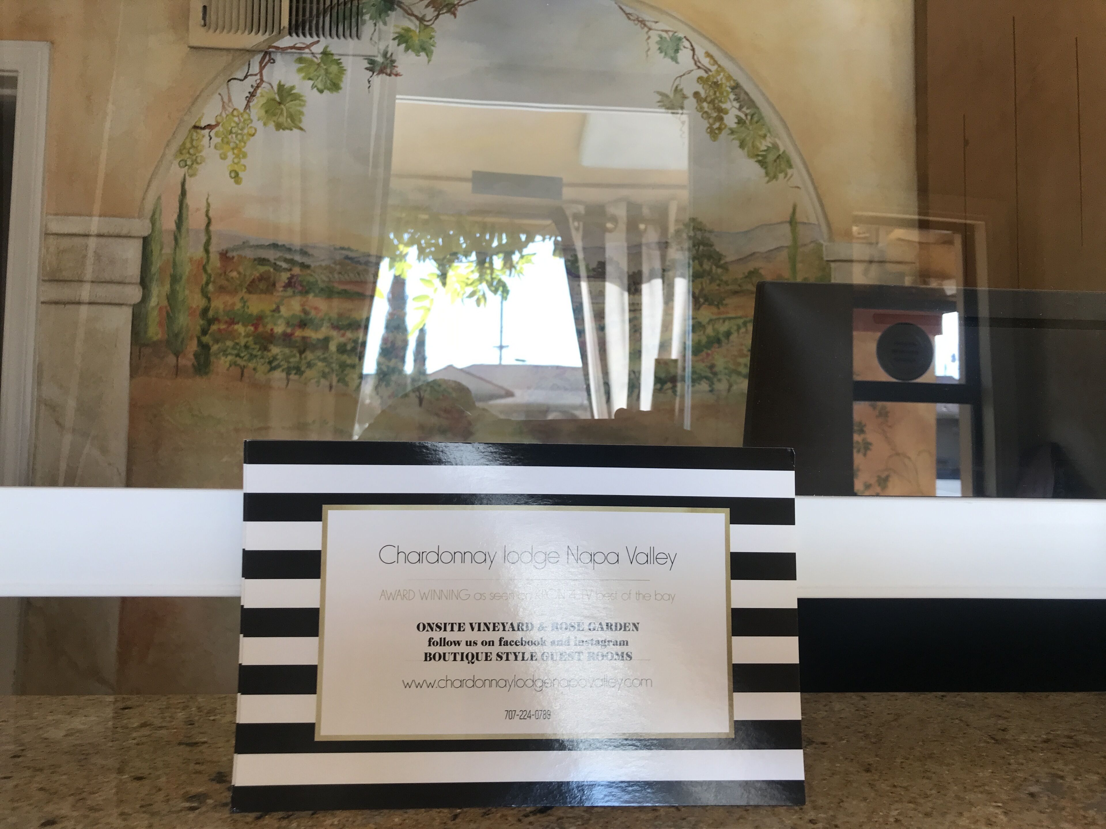 Une plaque encadrée avec le texte « Chardonnay Lodge Napa Valley », mentionnant la présence d’un vignoble et d’un jardin de roses sur le site, ainsi qu’une adresse URL.
