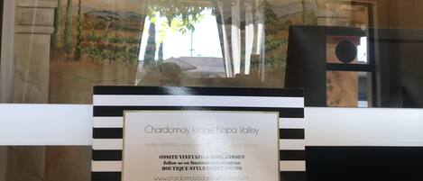 Une plaque encadrée avec le texte « Chardonnay Lodge Napa Valley », mentionnant la présence d’un vignoble et d’un jardin de roses sur le site, ainsi qu’une adresse URL.