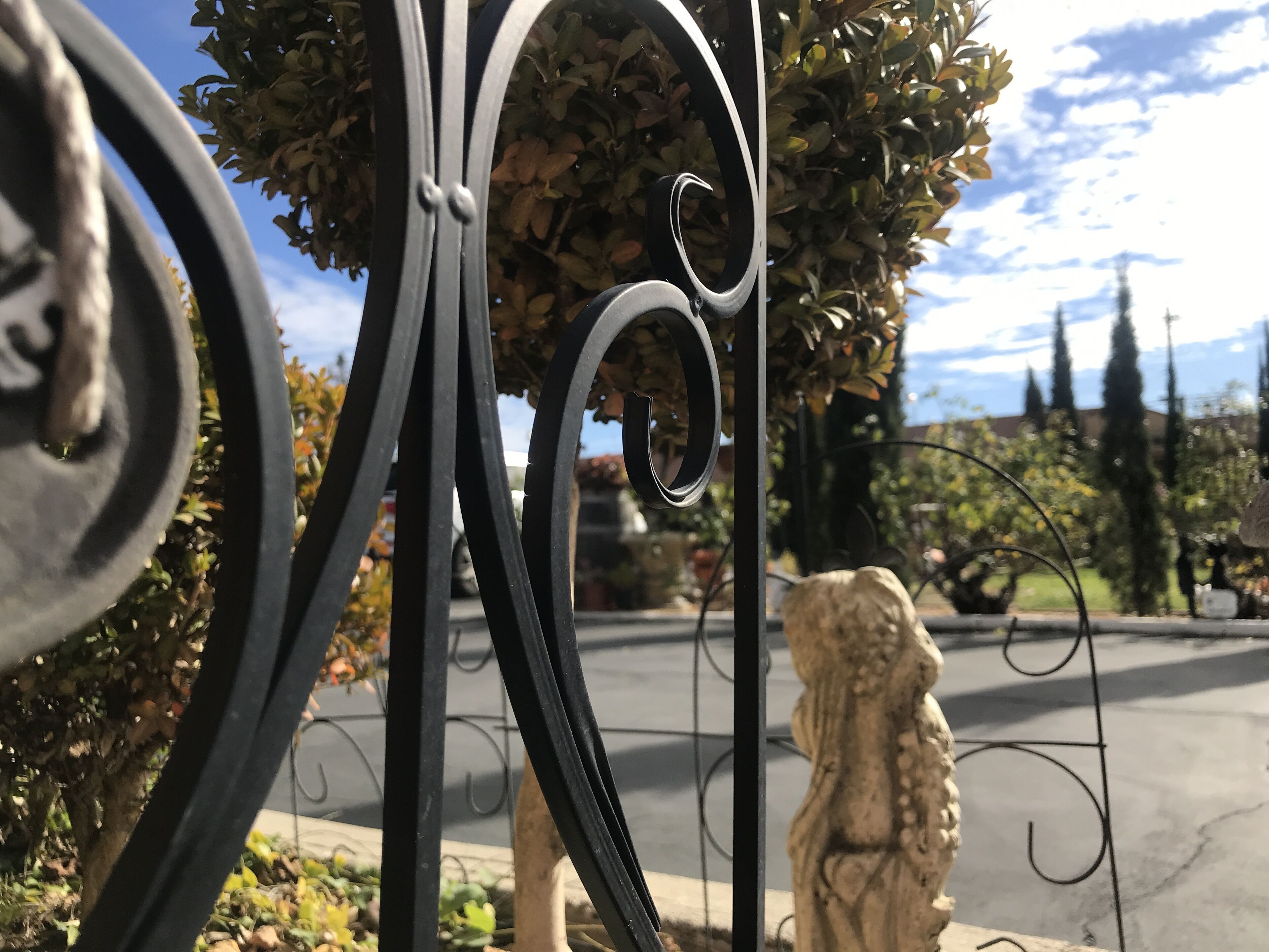 A wrought iron gate with a decorative lion statue in the background.