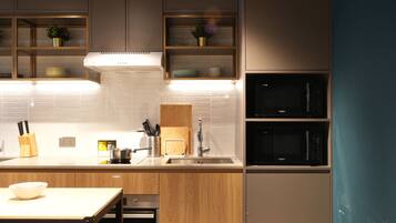 A modern kitchen with wooden cabinets, a stainless steel sink, and built-in appliances including a microwave and oven.