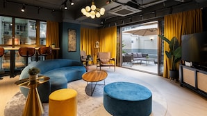 A modern interior with a blue sofa, yellow ottoman, and a round wooden table. - Dash Living On Hollywood (Hong Kong)