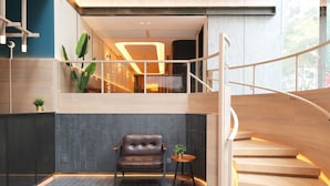 A modern interior with a staircase, a leather chair, and a small table with a plant. - Dash Living On Hollywood (Hong Kong)