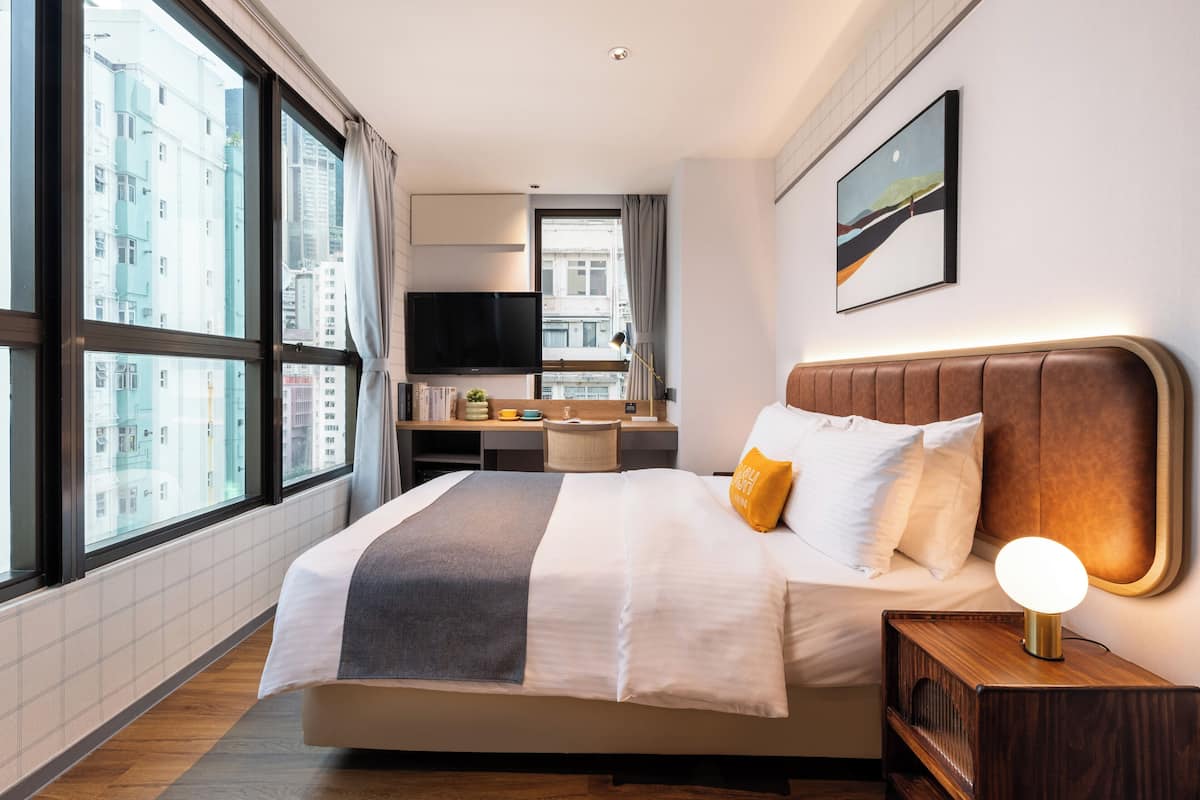 A modern hotel room with a large bed, a desk, and a TV.