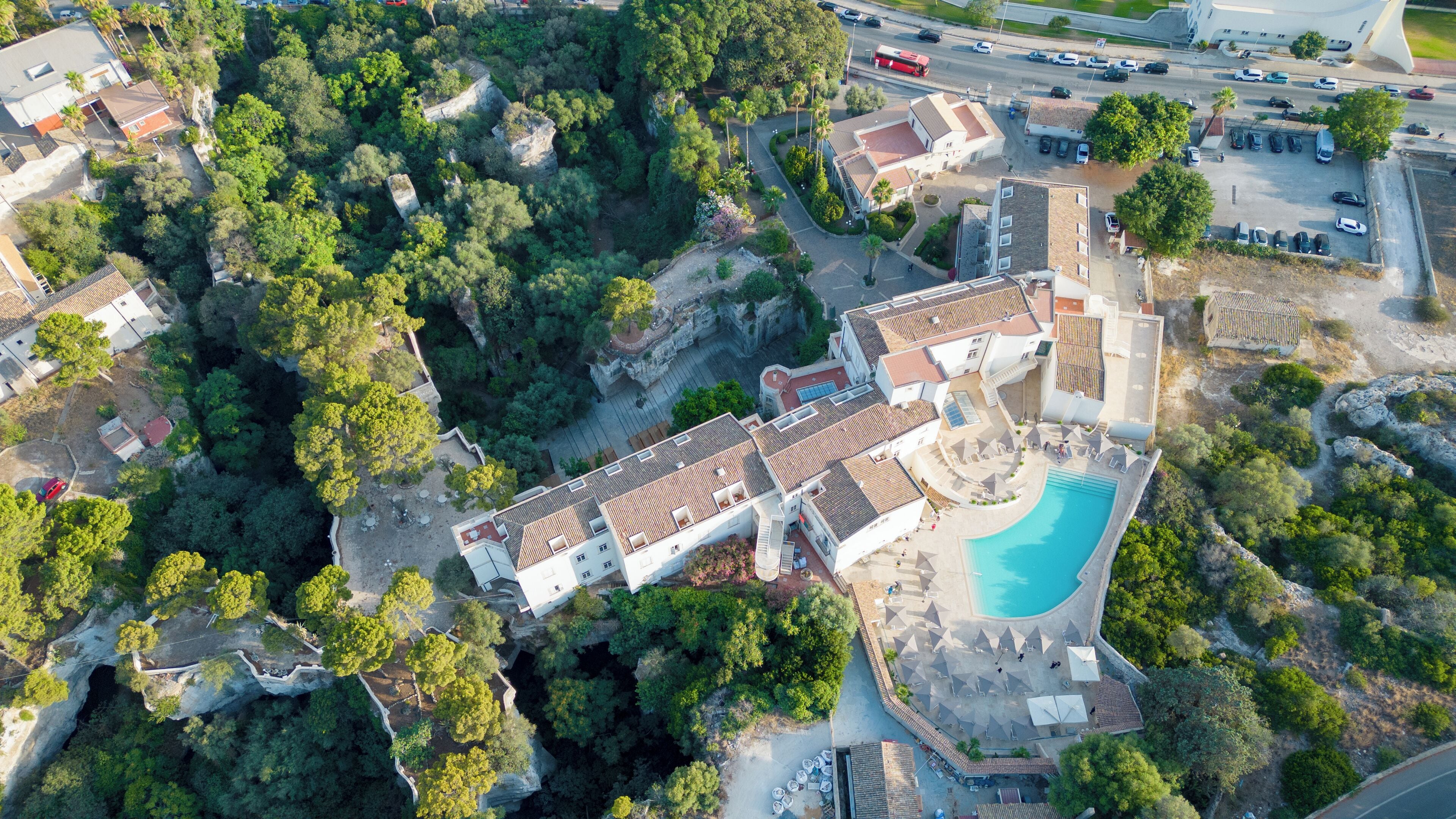 Luftaufnahme eines Resorts mit Schwimmbad, gestuften Gebäuden und üppiger Bepflanzung.