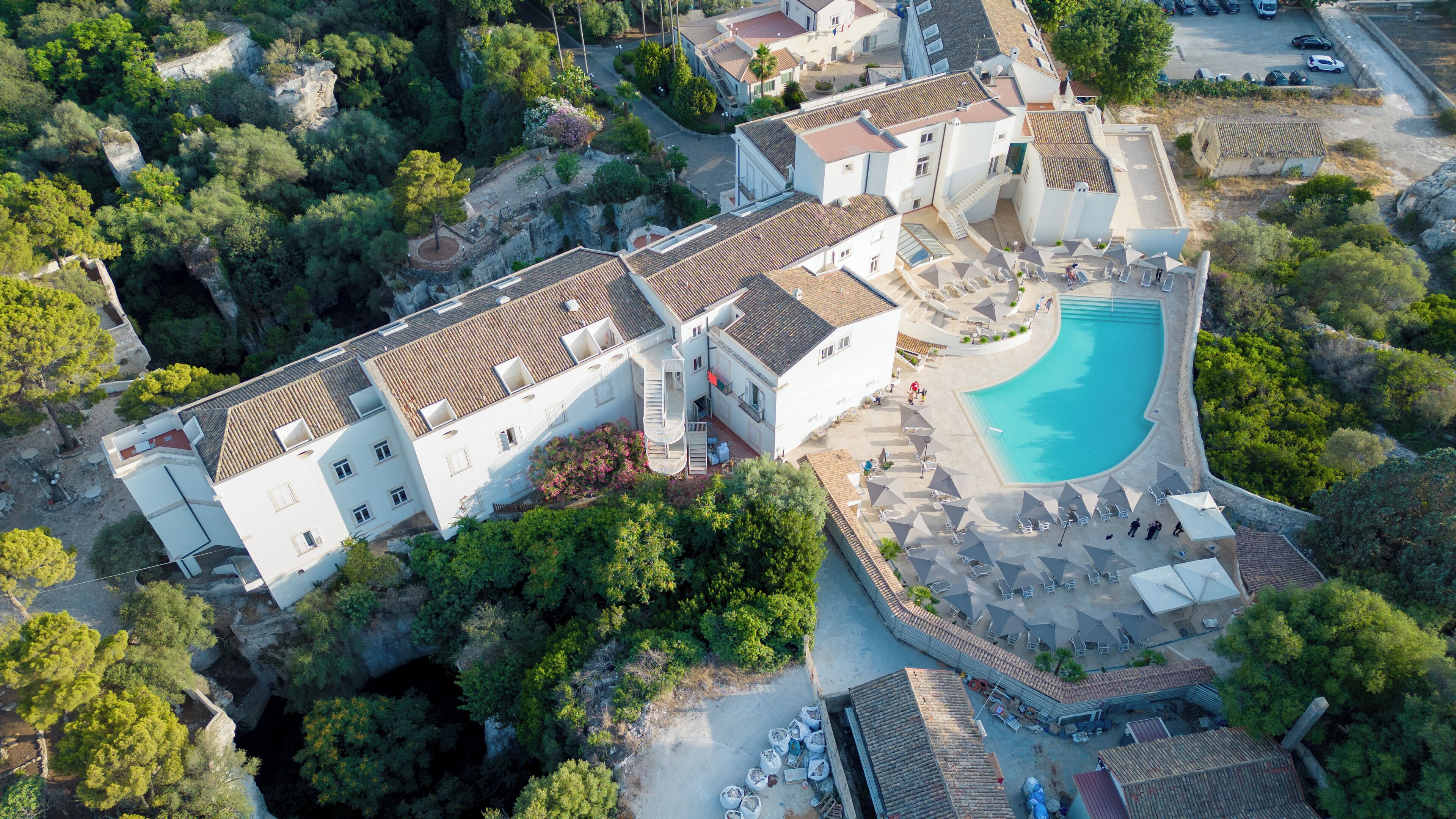 An aerial view of a resort with multiple buildings, a swimming pool, and lush greenery.