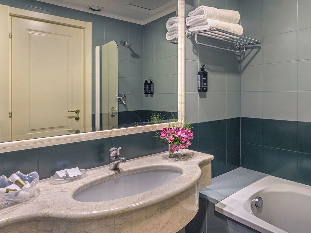 A bathroom with a sink, mirror, and bathtub.