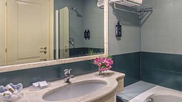 A bathroom with a sink, mirror, and bathtub.