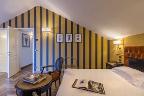 A hotel room with a bed, a desk, a chair, and a small table. There are framed pictures on the wall and a lamp on the desk. - Grand Hotel Villa Politi (Syracuse)