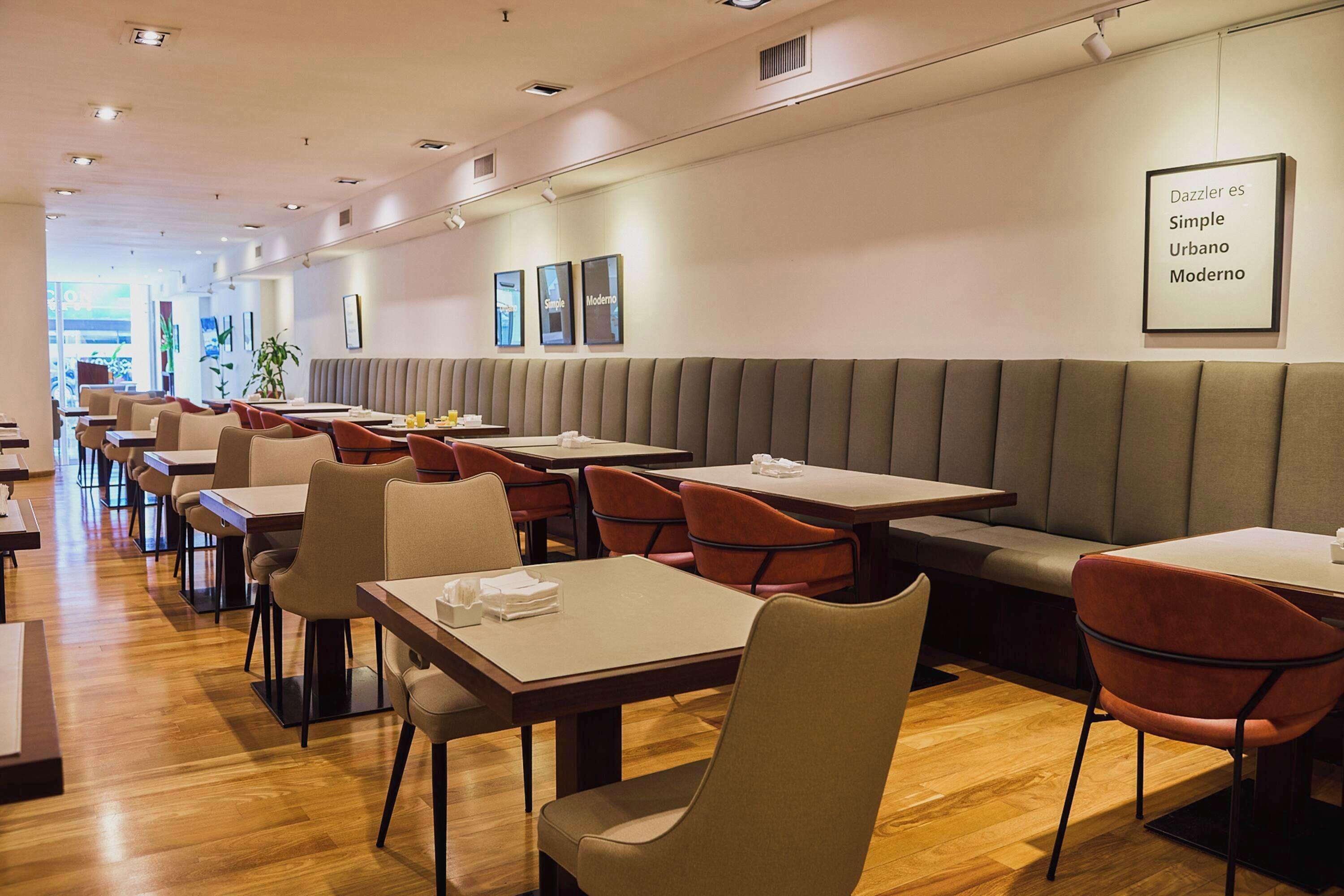 A modern restaurant interior with booths and tables, wooden flooring, and framed artwork on the walls.