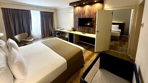A hotel room with a bed, desk, chair, TV, and a mirror.