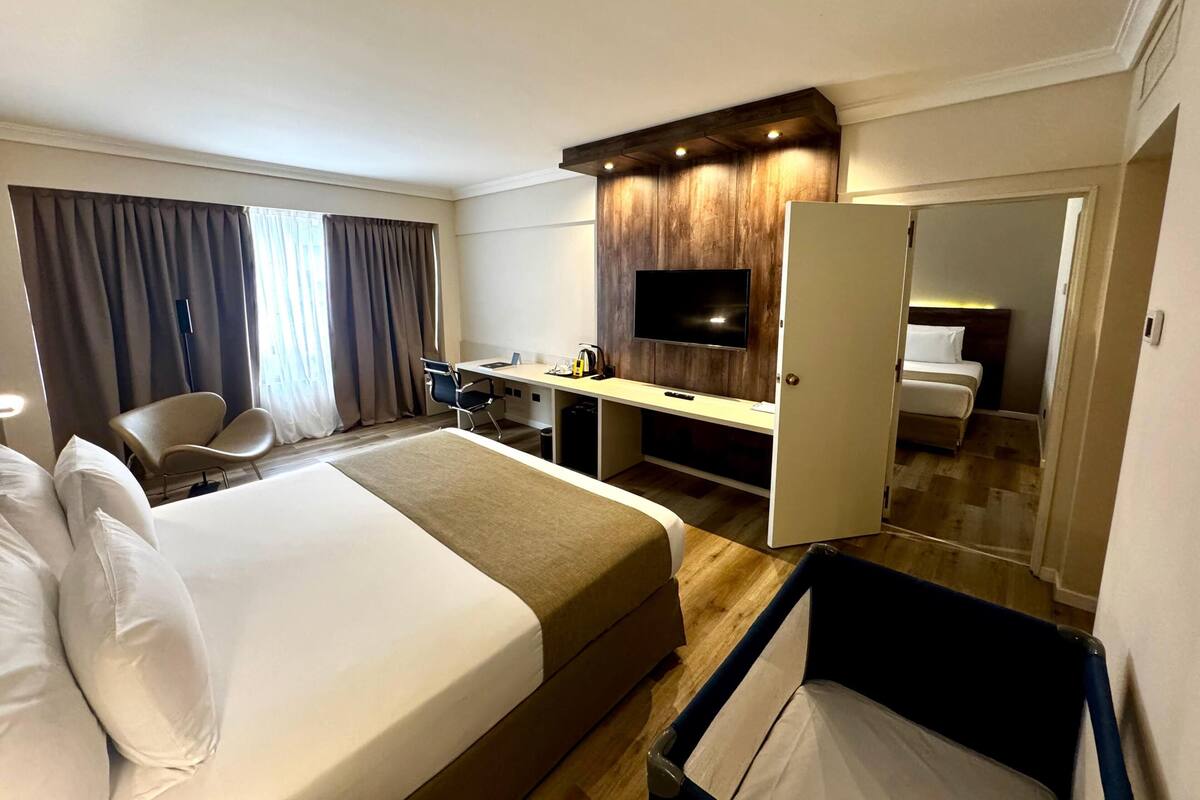 A hotel room with a bed, desk, chair, TV, and a mirror.