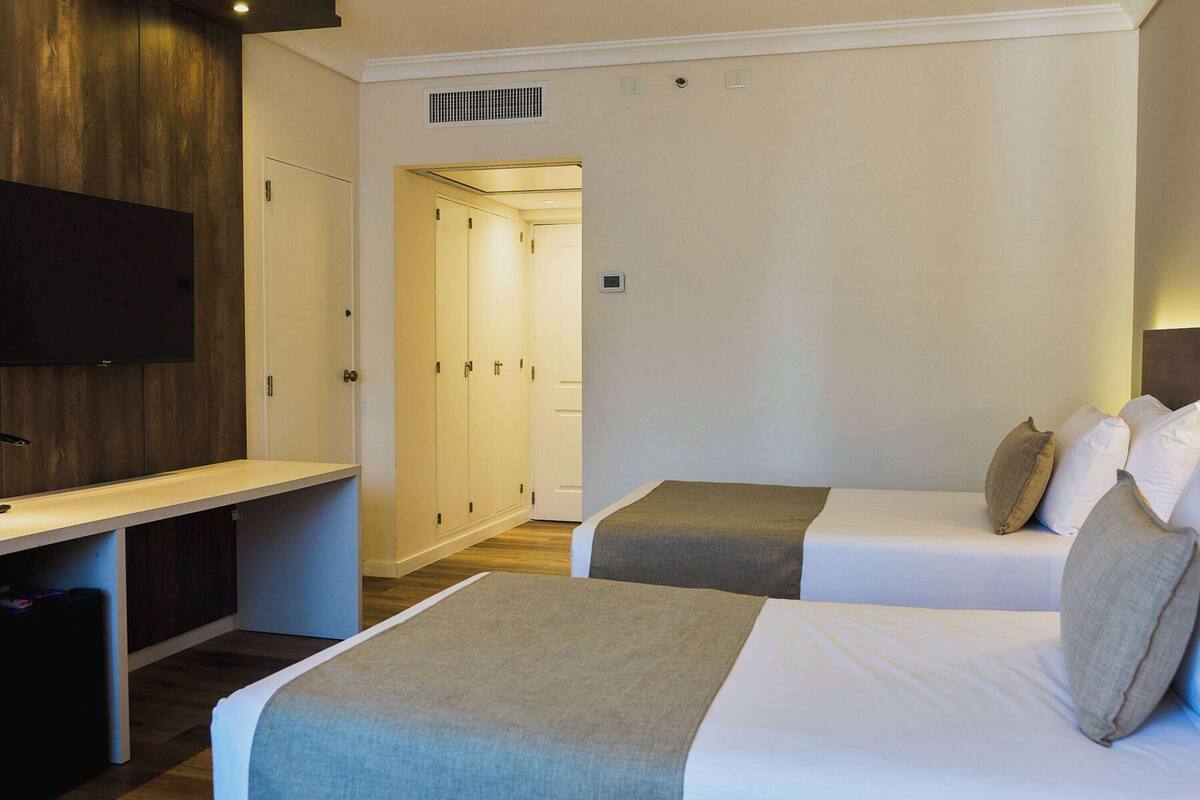 A hotel room with a bed, a desk, and a TV.