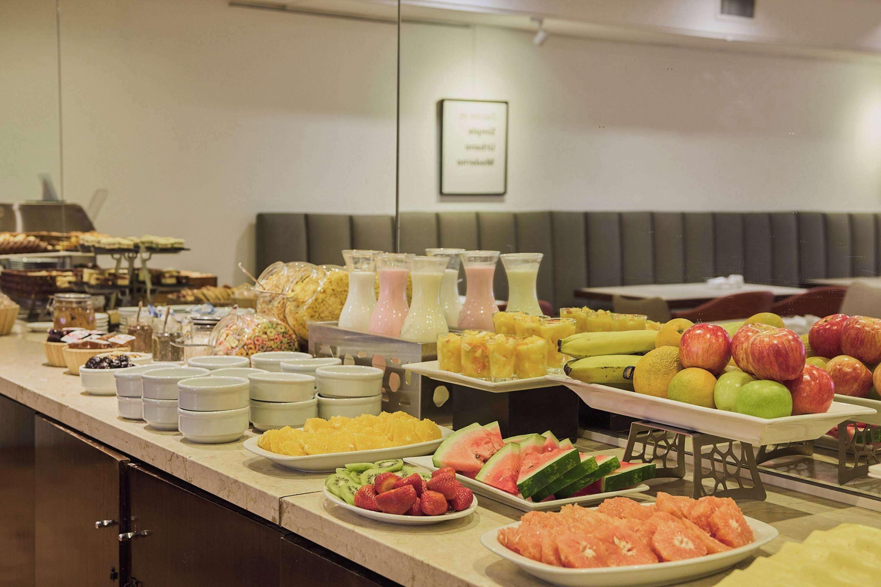 A buffet with various fruits, vegetables, and beverages.