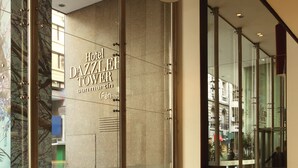 A modern hotel lobby with a large glass wall, a reception desk, and comfortable seating areas.