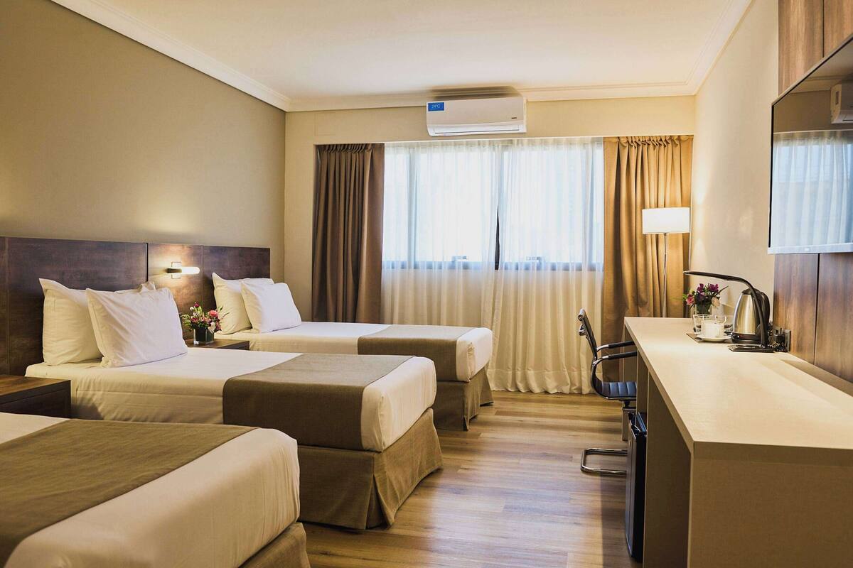 A hotel room with two beds, a desk, and a chair.