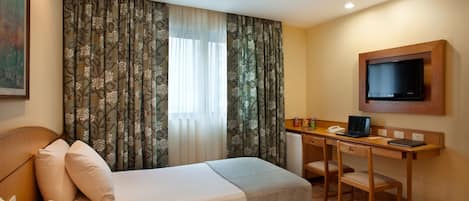 Une chambre d’hôtel avec deux lits, un bureau avec un ordinateur portable, une télévision et un petit réfrigérateur.