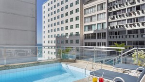A rooftop pool with lounge chairs and a glass balustrade, surrounded by a high-rise building. - Windsor Martinique Copacabana (Rio de Janeiro)