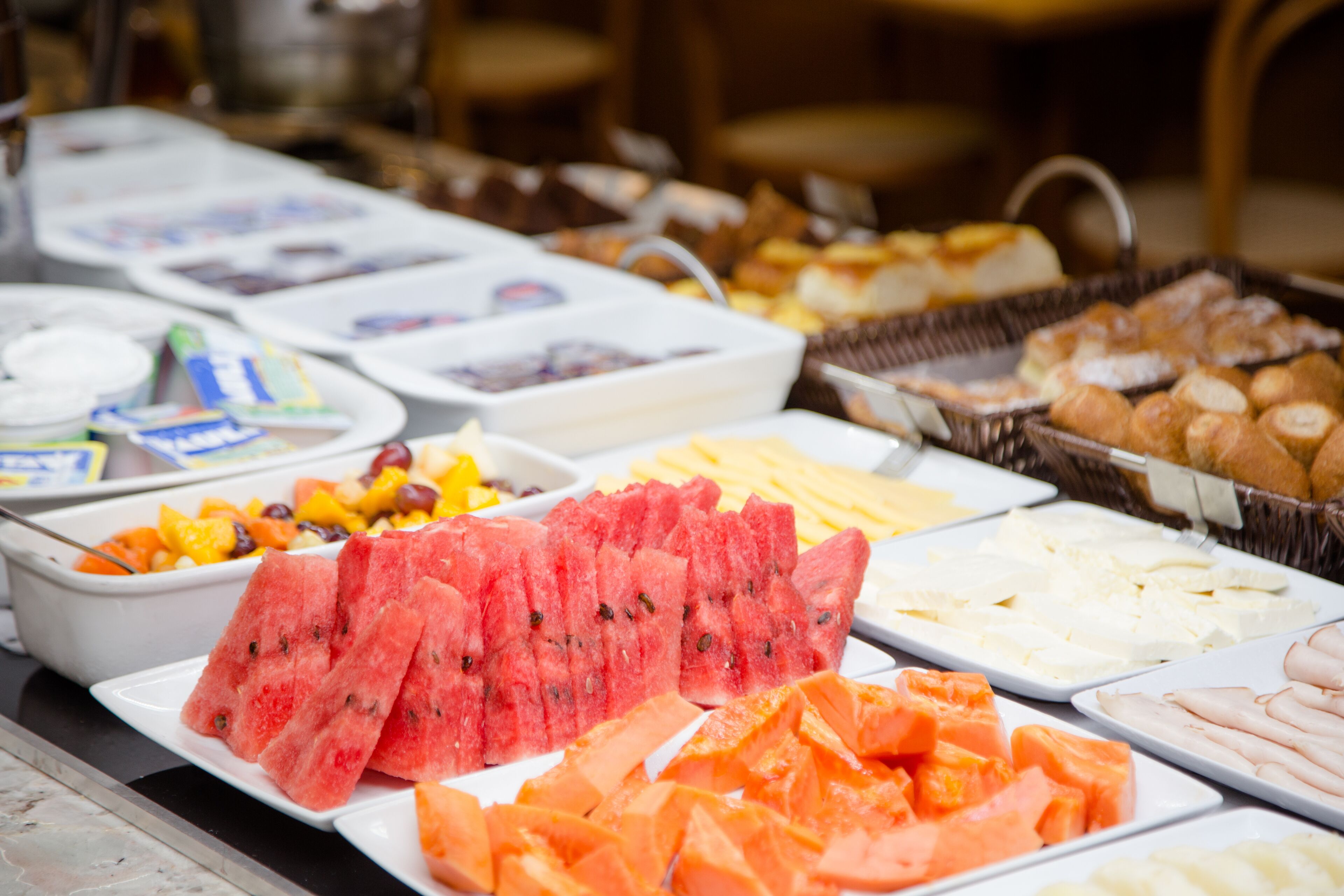A buffet with various food items including watermelon, cheese, and pastries.