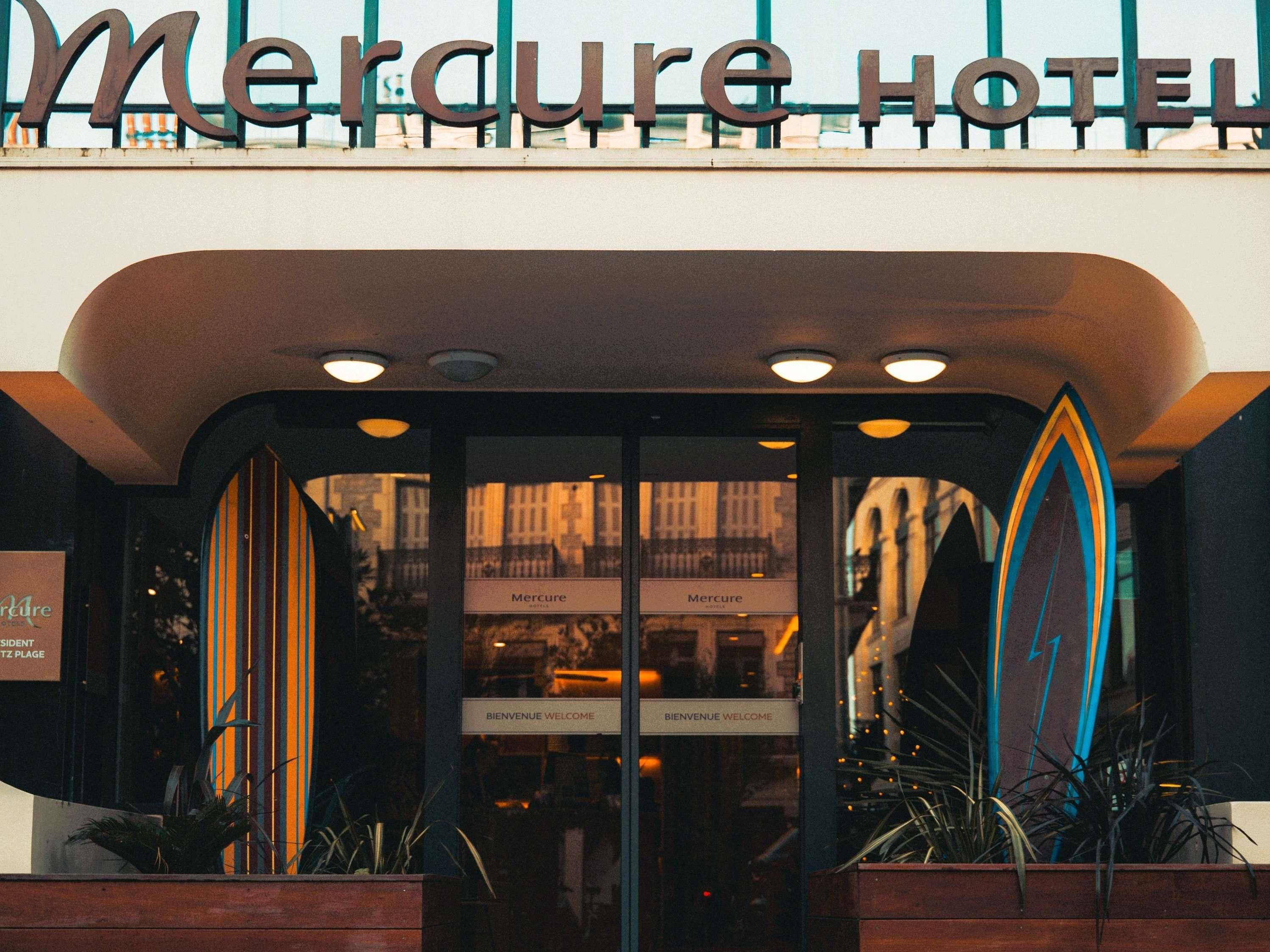 Exterior del hotel Mercure, con un cartel sobre la entrada y un letrero de bienvenida en el interior.