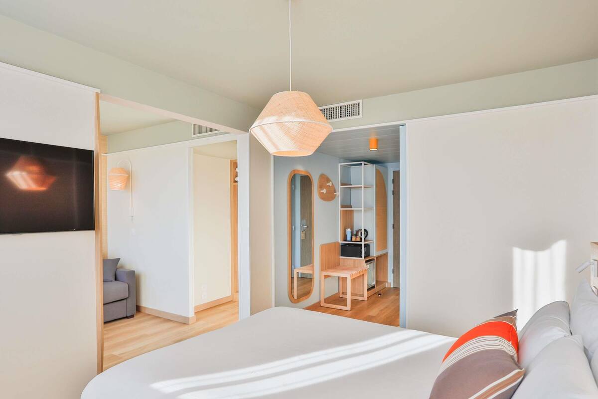 A modern bedroom with a bed, a TV, a desk, and a chair.