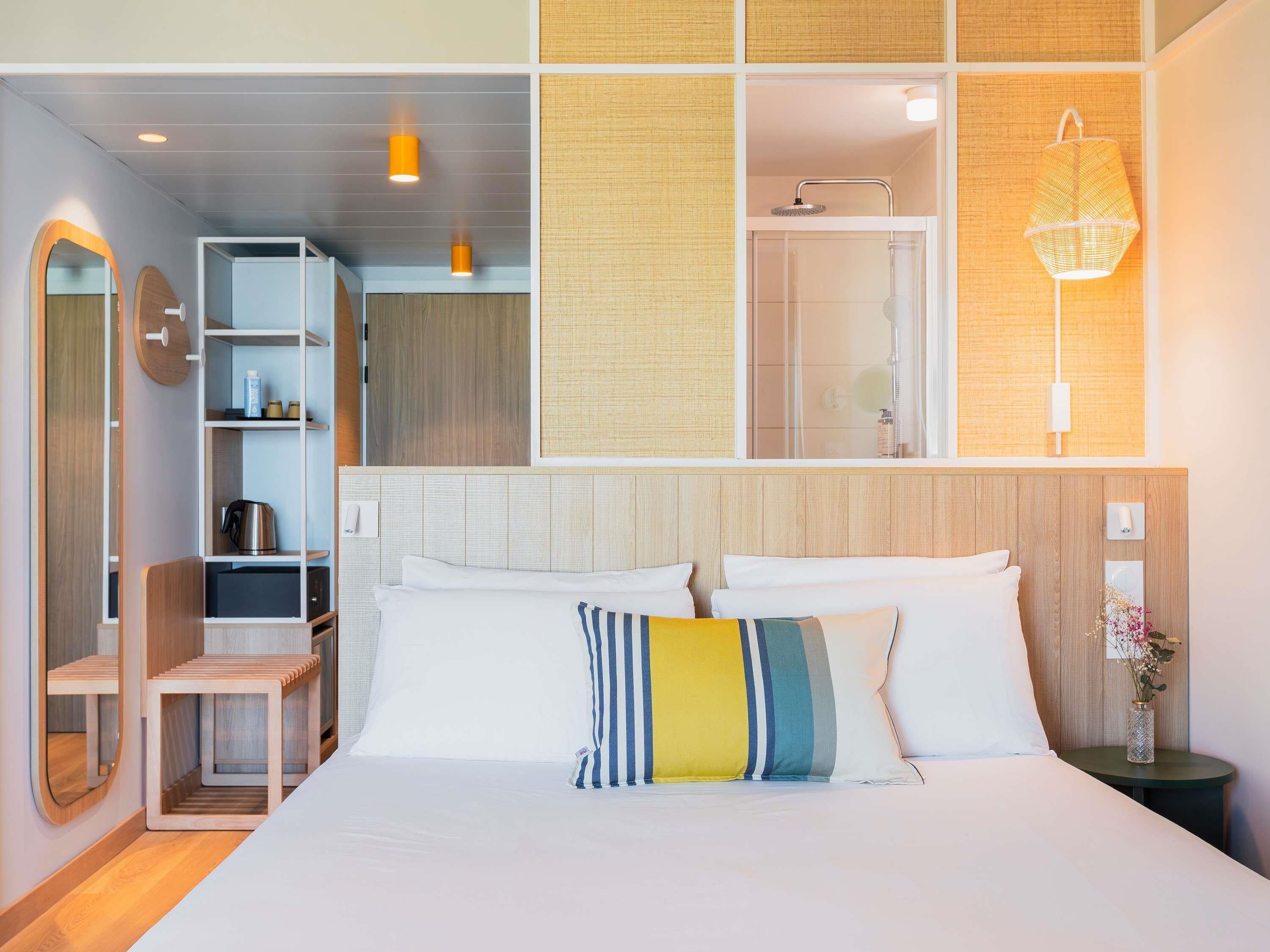 Una habitación de hotel moderna con cama, mesita de noche y zona de ducha.