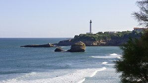 A coastal scene with a lighthouse, rocky outcrops, and a beach.