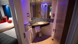 A modern bathroom with a sink, mirror, and towel rack.