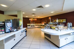 Een modern ontbijtbuffet met een koffieapparaat, een koelkast en diverse etenswaren.