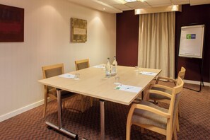 Ein Konferenzraum mit Tisch, Stühlen, einer Tafel und einem Vorhang.