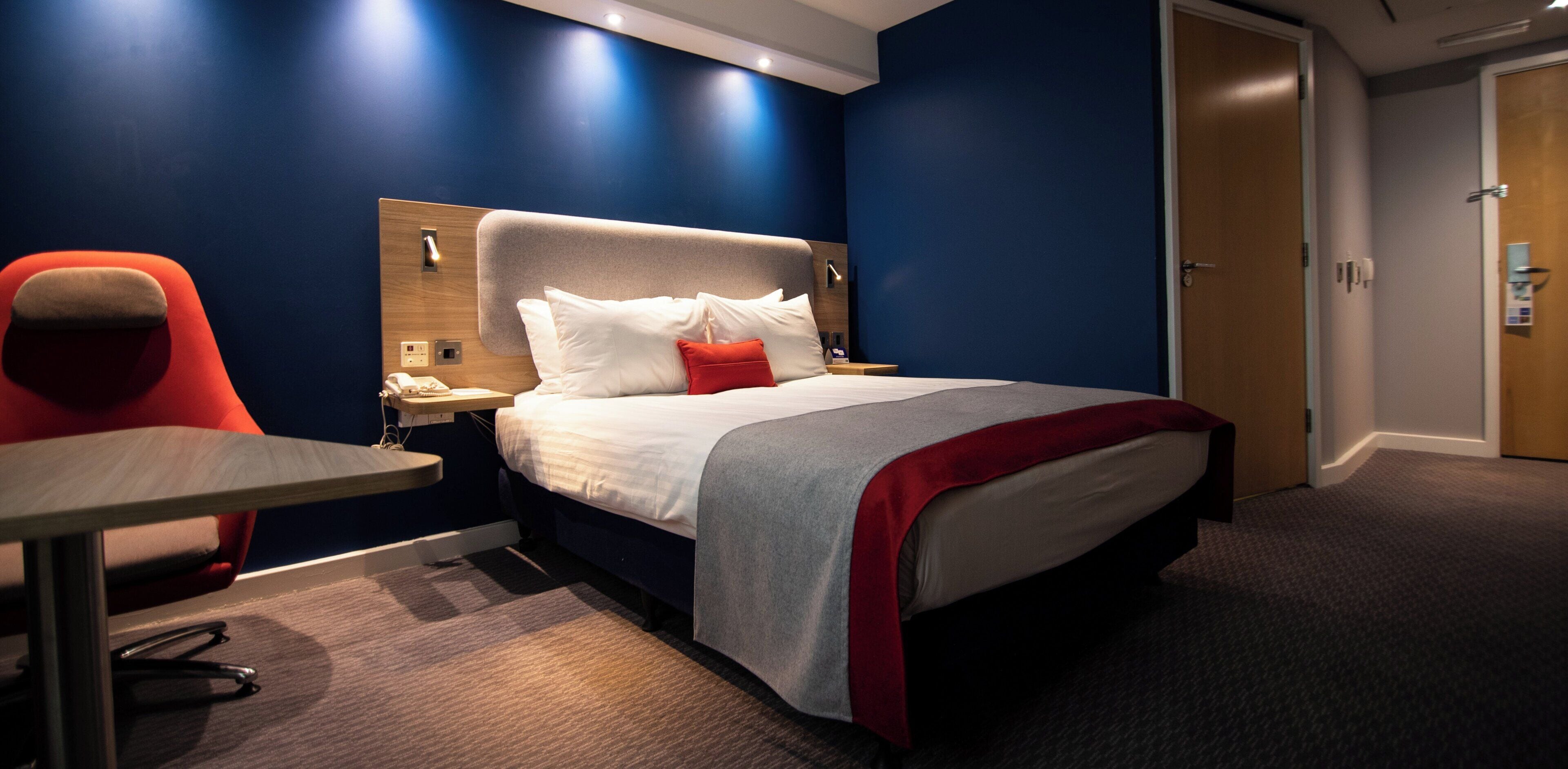 A hotel room with a bed, a desk, and a chair.