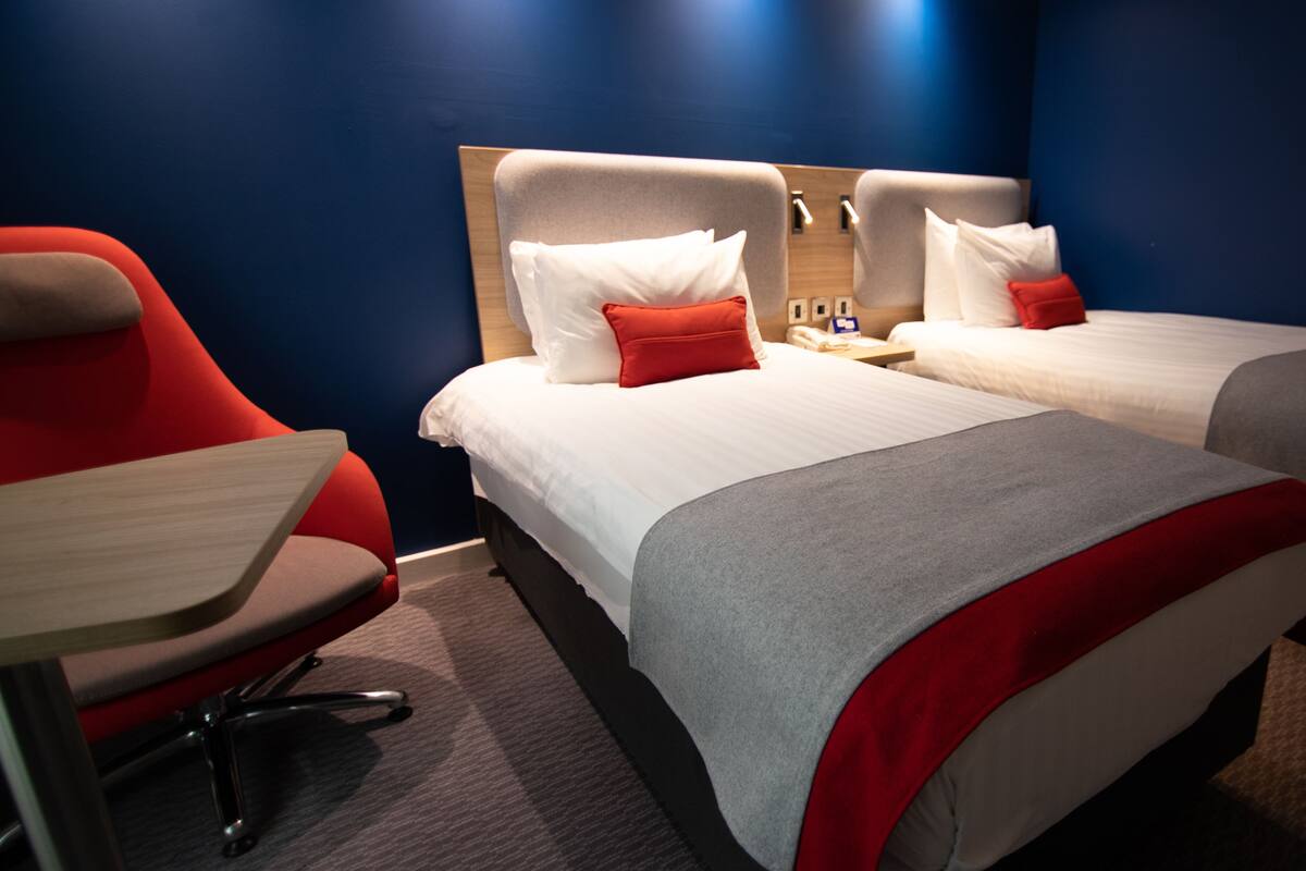 Een hotelkamer met twee bedden, een bureau en een stoel.
