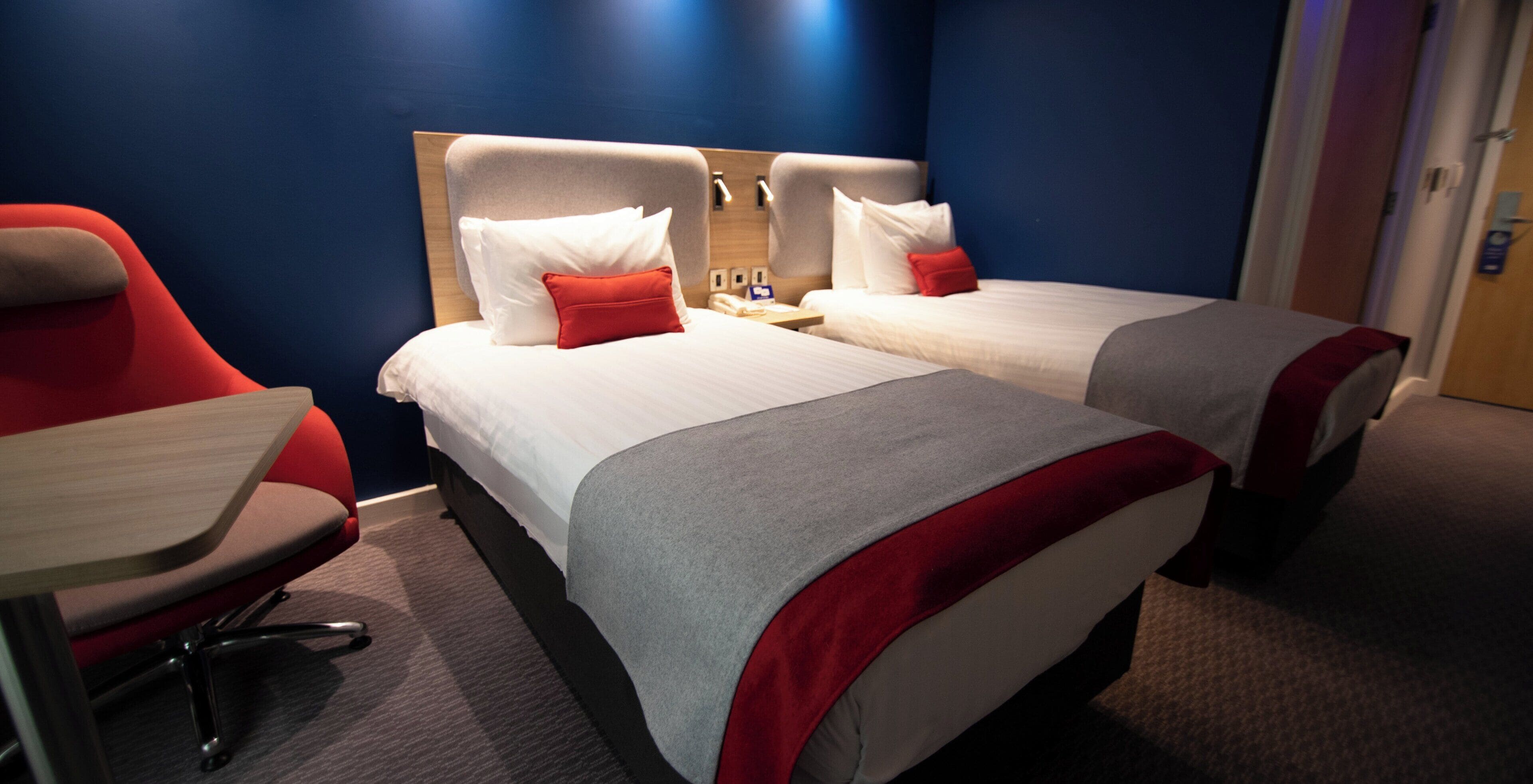 A hotel room with two beds, a desk, and a chair.