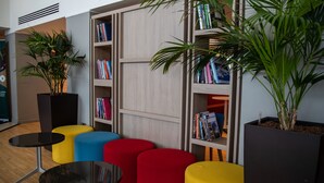 A modern library with colorful seating, bookshelves, and potted plants.