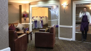Un hall de hotel con asientos de cuero, una recepción y un espacio para eventos decorado.