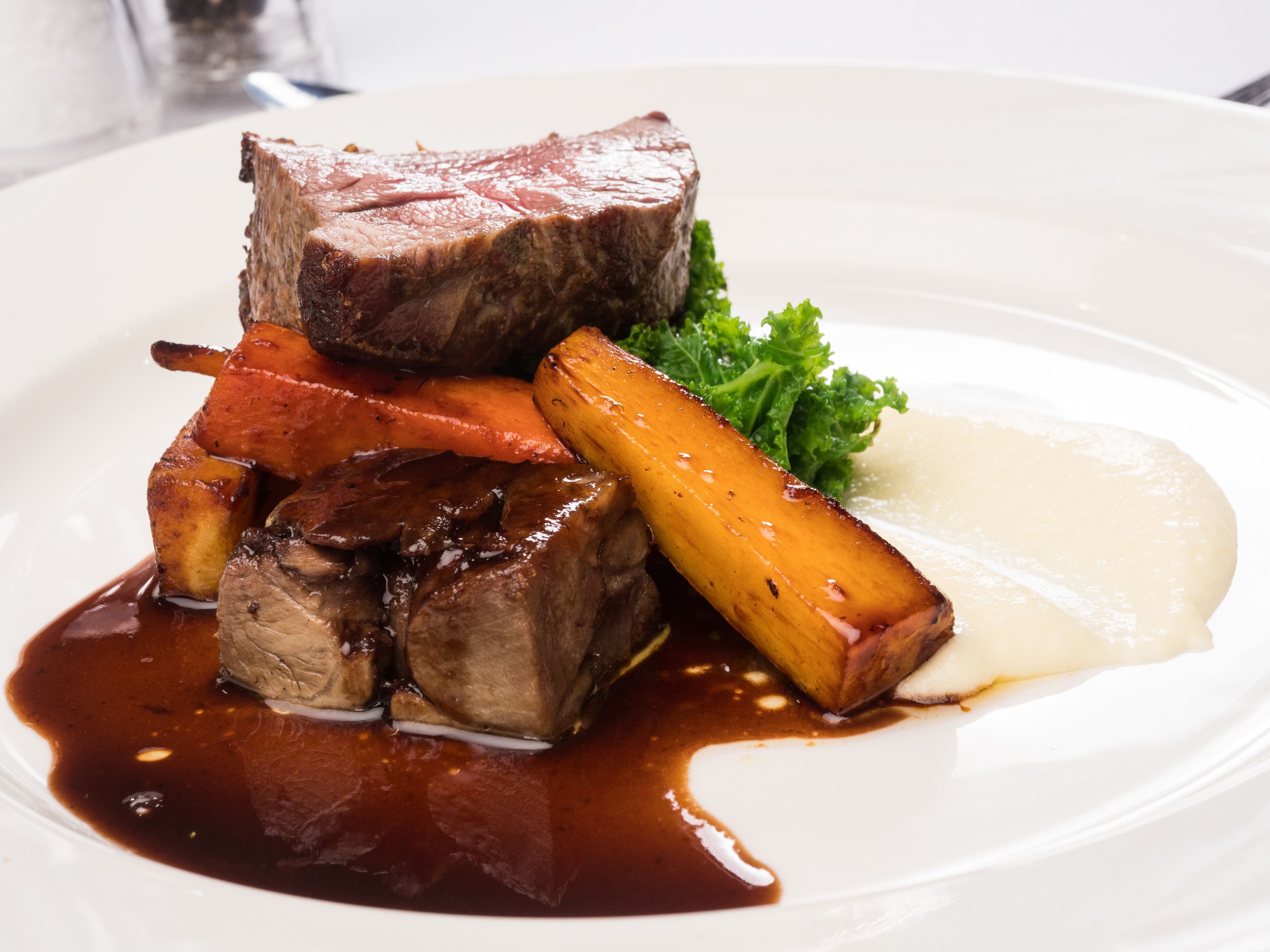 A plate of food with steak, carrots, and potatoes.