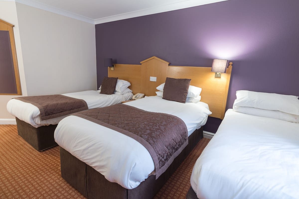 Habitació d'hotel amb dos llits individuals, cadascun amb capçalera de fusta, roba de llit blanca i una manta marró.