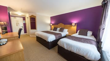 Une chambre d’hôtel avec deux lits, un bureau et une chaise.