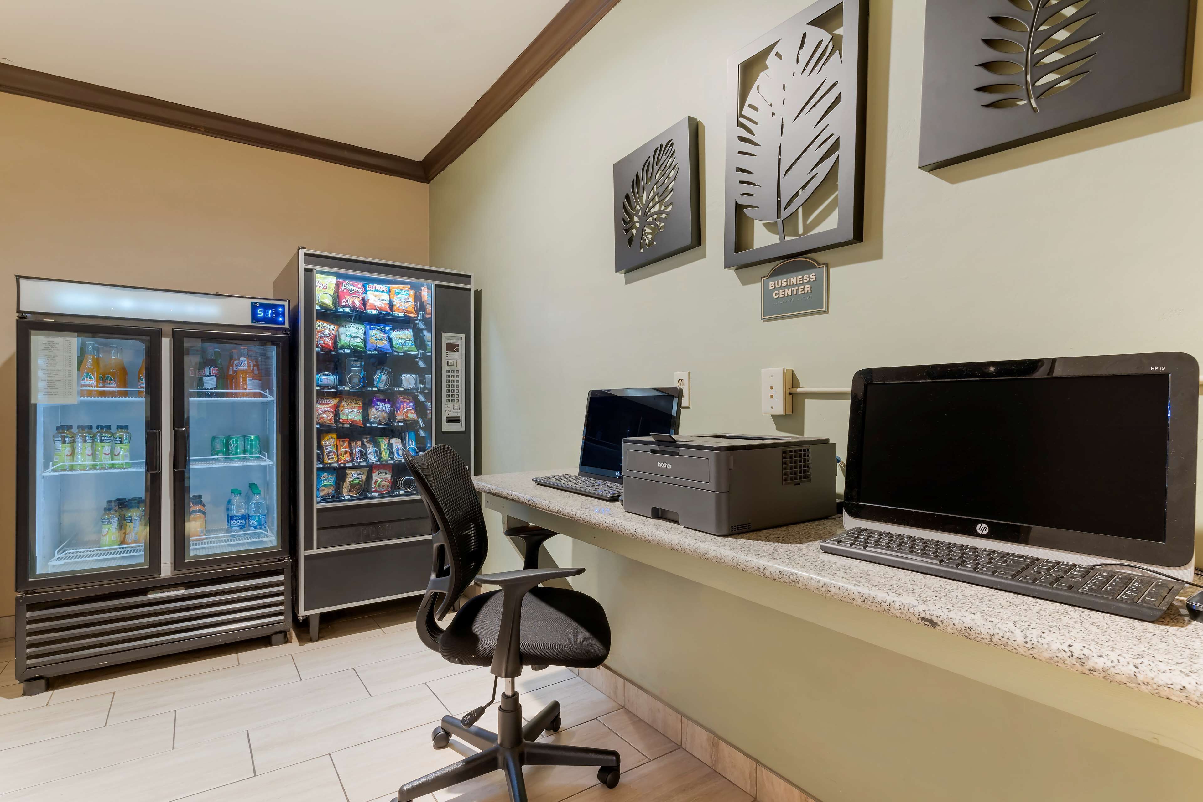 A business center with two beverage dispensers, a desktop computer, and a printer.
