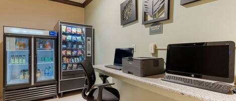 A business center with two beverage dispensers, a desktop computer, and a printer.