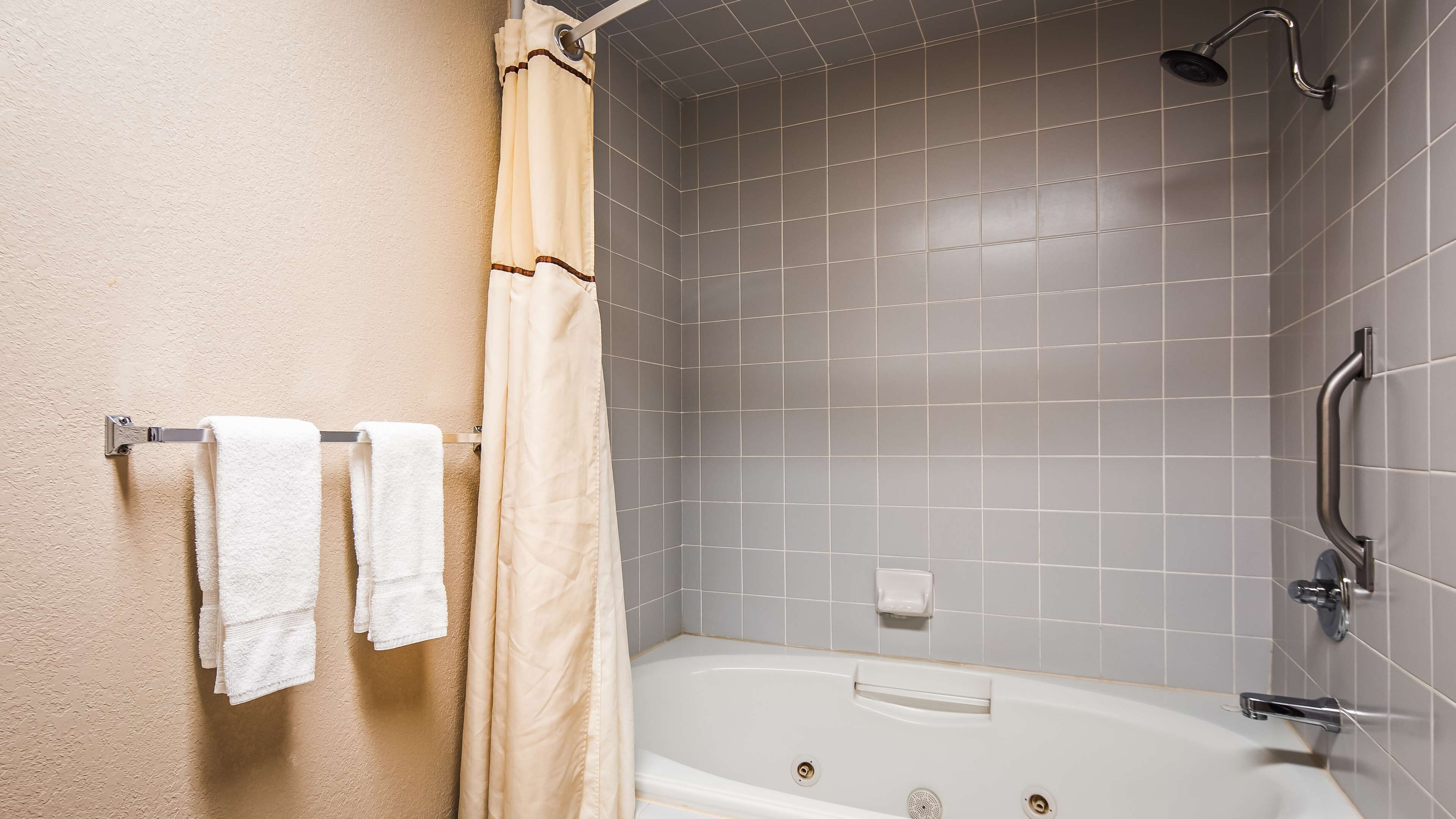 A bathroom with a bathtub, shower, and towel rack with towels.