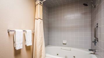 A bathroom with a bathtub, shower, and towel rack with towels.