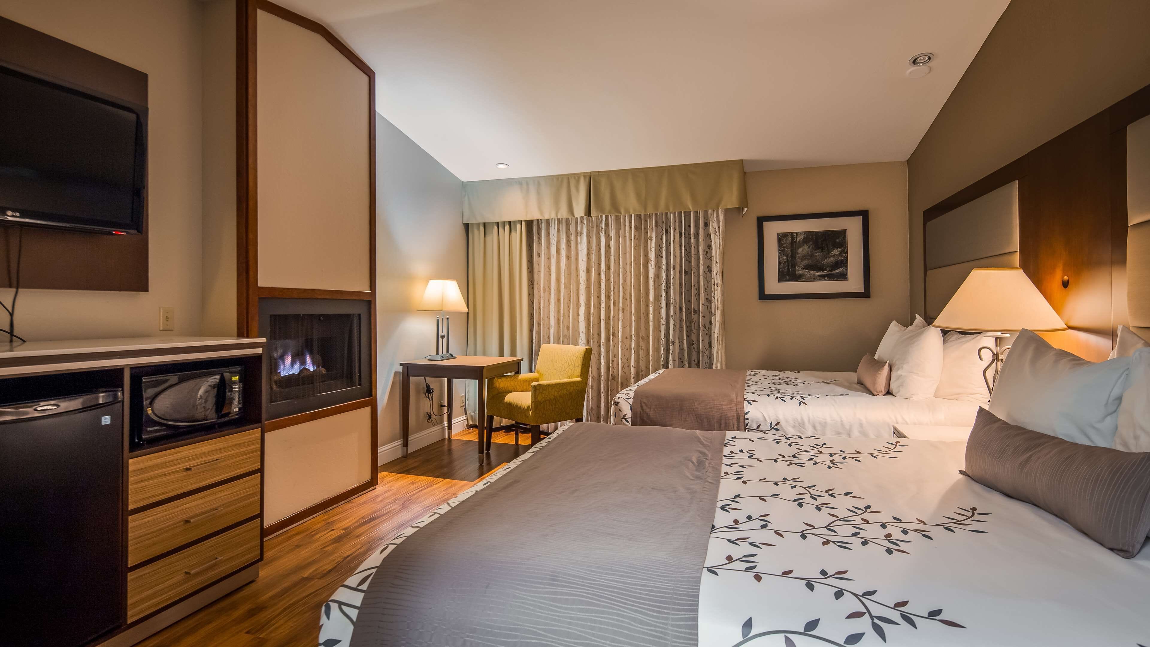 A hotel room with a bed, a desk, a chair, a TV, and a microwave.