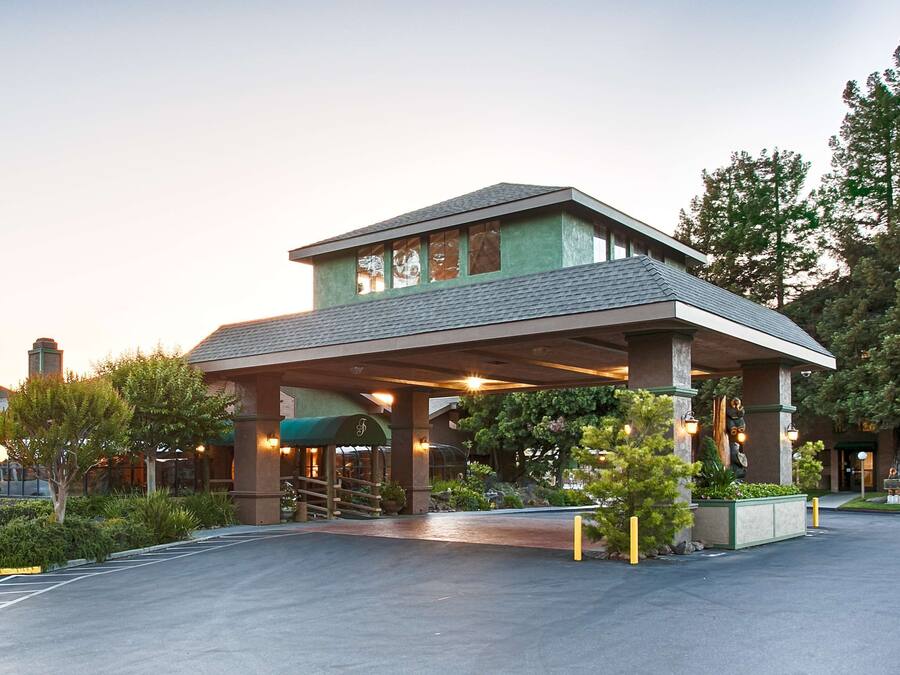 A hotel with a covered entrance, outdoor seating area, and a parking lot.